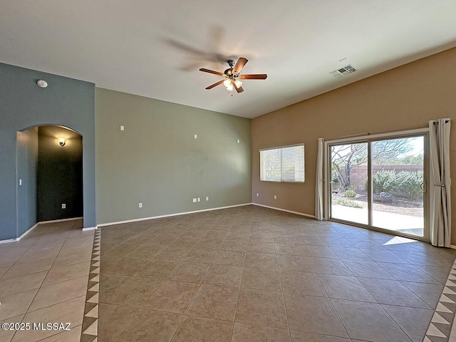 spare room featuring arched walkways, light tile patterned flooring, visible vents, baseboards, and a ceiling fan