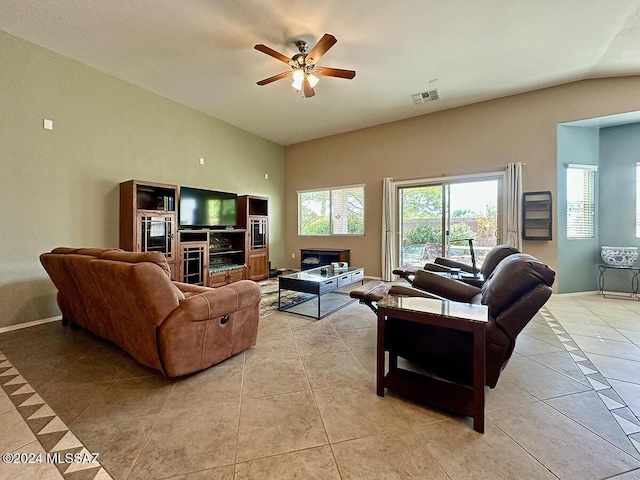 living area featuring lofted ceiling, visible vents, light tile patterned flooring, ceiling fan, and baseboards