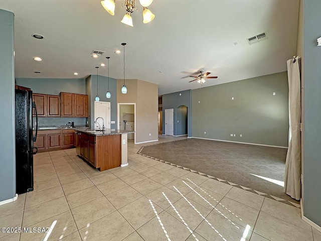 kitchen featuring brown cabinetry, open floor plan, a kitchen island with sink, and a sink