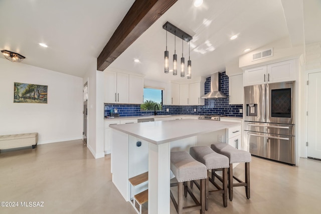 kitchen with stainless steel fridge with ice dispenser, a kitchen island, wall chimney exhaust hood, and white cabinets