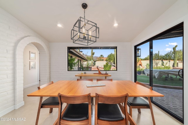 dining area featuring brick wall and a chandelier