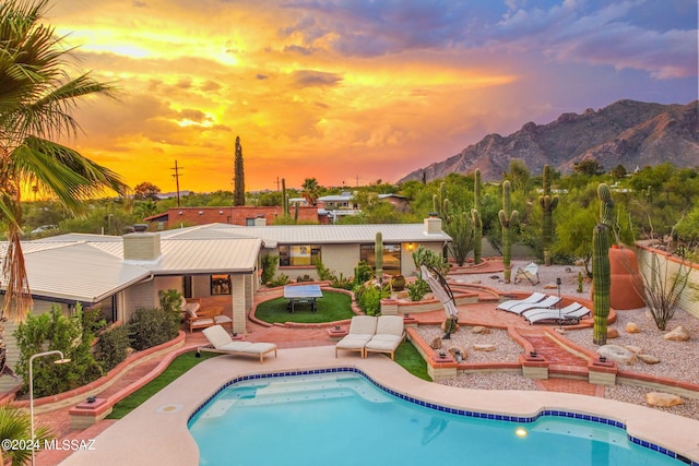 pool at dusk featuring a patio area and a mountain view