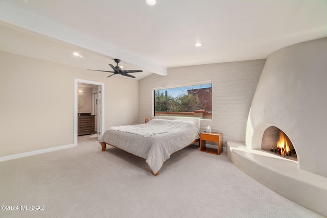 bedroom featuring ceiling fan, a fireplace, light carpet, and vaulted ceiling with beams