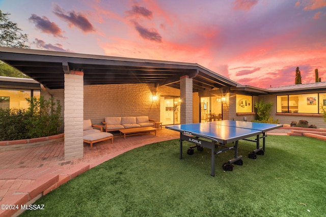 patio terrace at dusk featuring an outdoor living space and a lawn