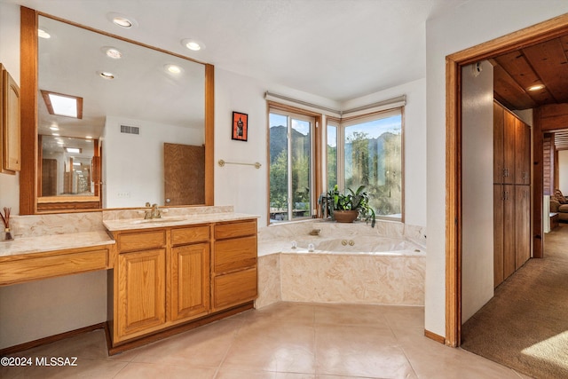 bathroom with vanity, a skylight, tile patterned floors, and tiled bath