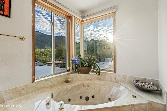 bathroom featuring a healthy amount of sunlight, tiled tub, and a mountain view