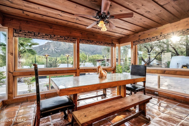 sunroom / solarium featuring wood ceiling, ceiling fan, a wealth of natural light, and a mountain view