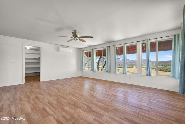 interior space featuring a wall mounted air conditioner, hardwood / wood-style floors, and ceiling fan