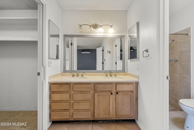 bathroom featuring tile patterned flooring, toilet, a textured ceiling, and vanity