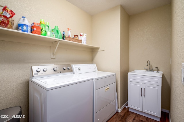 washroom with dark hardwood / wood-style floors, cabinets, washing machine and clothes dryer, and sink