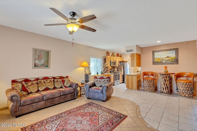 living room featuring a textured ceiling, light tile patterned flooring, and ceiling fan