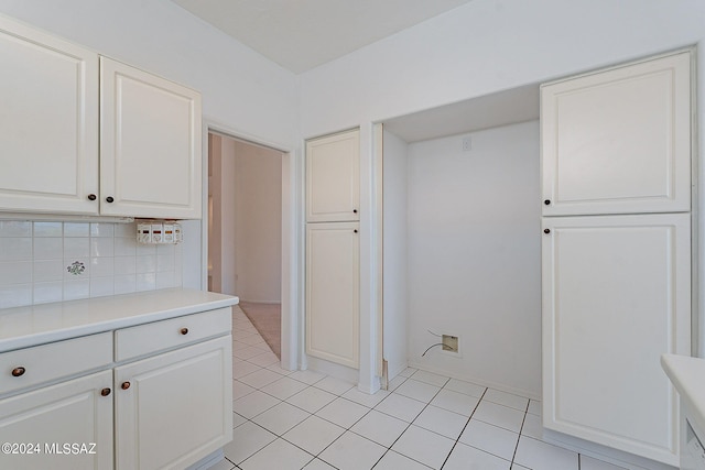 kitchen with tasteful backsplash, light tile patterned flooring, and white cabinets