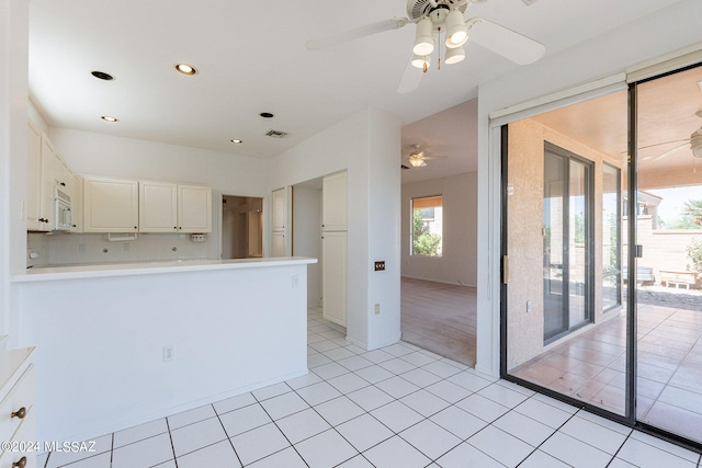 kitchen featuring white cabinets, ceiling fan, light tile patterned floors, and decorative backsplash