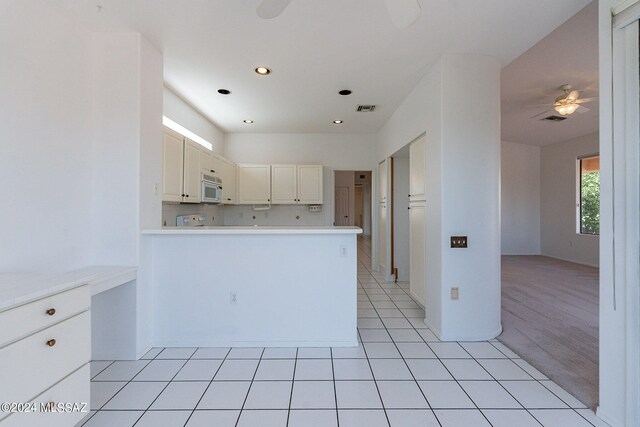 kitchen with light tile patterned floors, tasteful backsplash, kitchen peninsula, white cabinetry, and ceiling fan