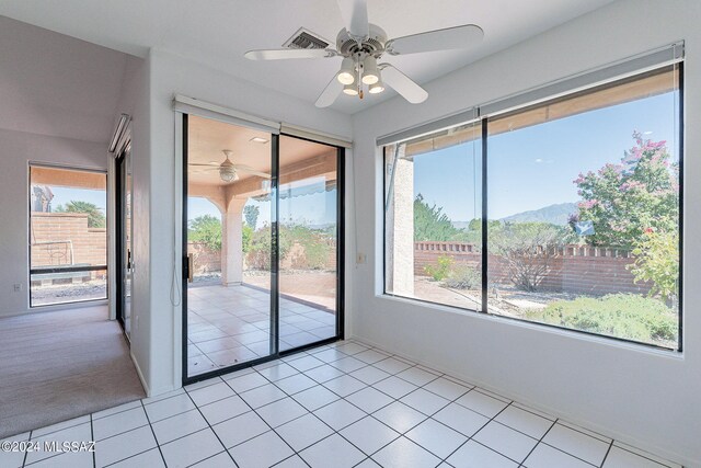 spare room with ceiling fan, light tile patterned floors, plenty of natural light, and a mountain view