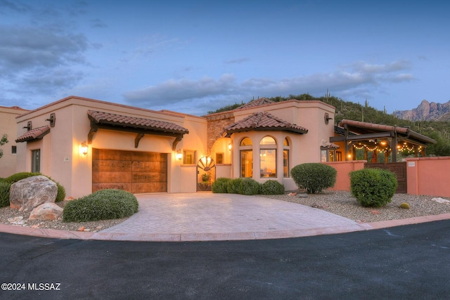 mediterranean / spanish house featuring fence, stucco siding, a garage, a tiled roof, and decorative driveway