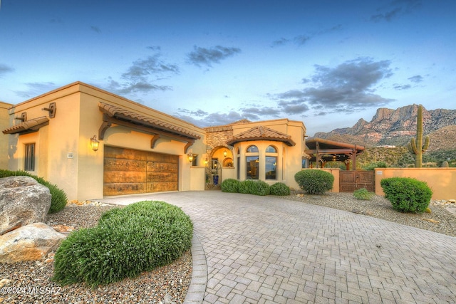 view of front of home with decorative driveway, an attached garage, a mountain view, and stucco siding