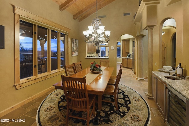 dining space with beverage cooler, beamed ceiling, wood ceiling, stone tile flooring, and arched walkways