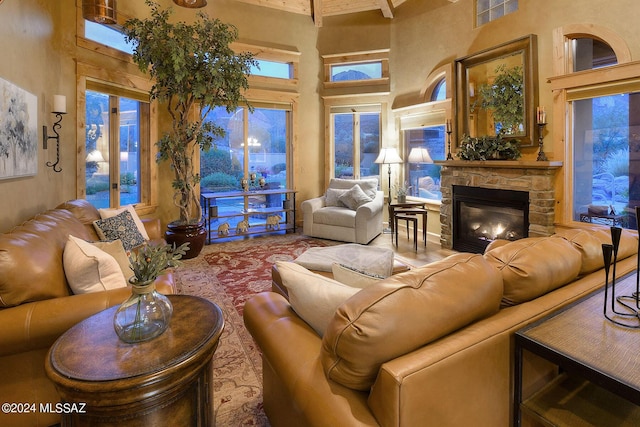 living area featuring a stone fireplace, a high ceiling, and visible vents