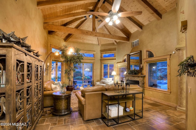 living room with ceiling fan, high vaulted ceiling, a stone fireplace, wooden ceiling, and beamed ceiling