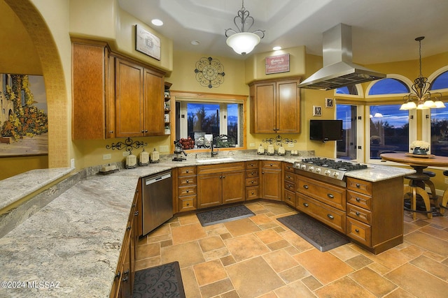 kitchen featuring a peninsula, brown cabinets, island exhaust hood, a sink, and appliances with stainless steel finishes