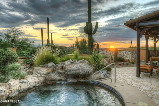 pool at dusk featuring fence and a patio area