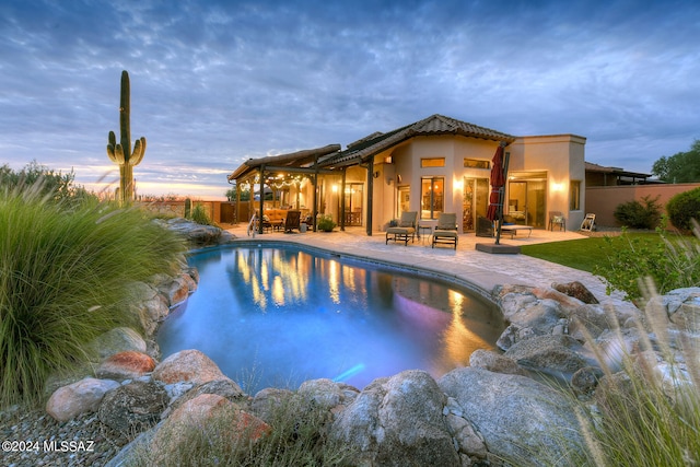 pool at dusk with an outdoor hangout area and a patio area