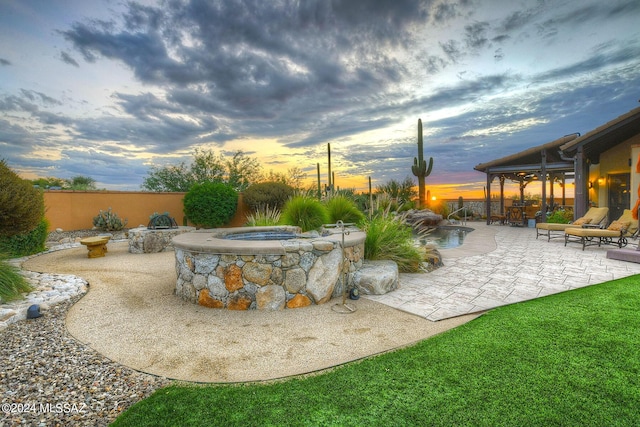 yard at dusk with fence, a patio, and a fire pit