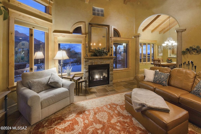 living room featuring beamed ceiling, a towering ceiling, a notable chandelier, and a fireplace