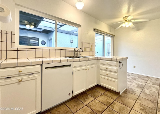 kitchen with white cabinetry, sink, tile countertops, white dishwasher, and decorative backsplash