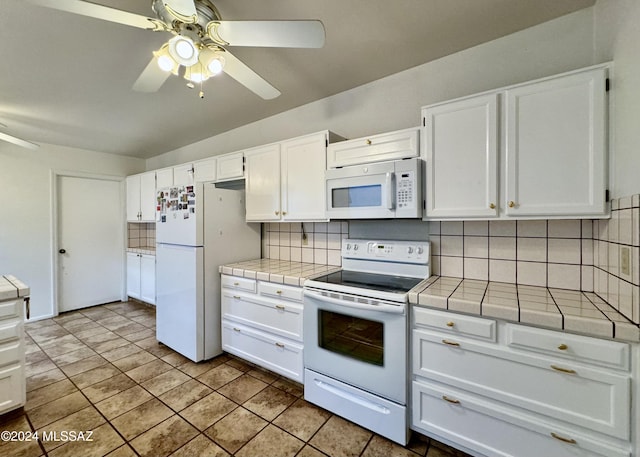 kitchen featuring tile countertops, decorative backsplash, white cabinets, and white appliances