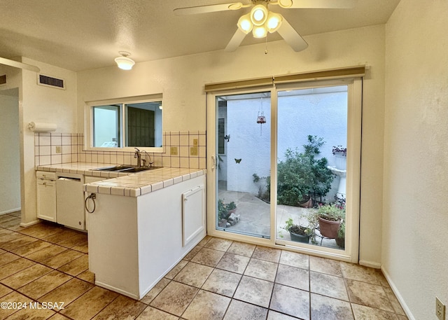 kitchen featuring tile counters, white cabinetry, sink, and tasteful backsplash