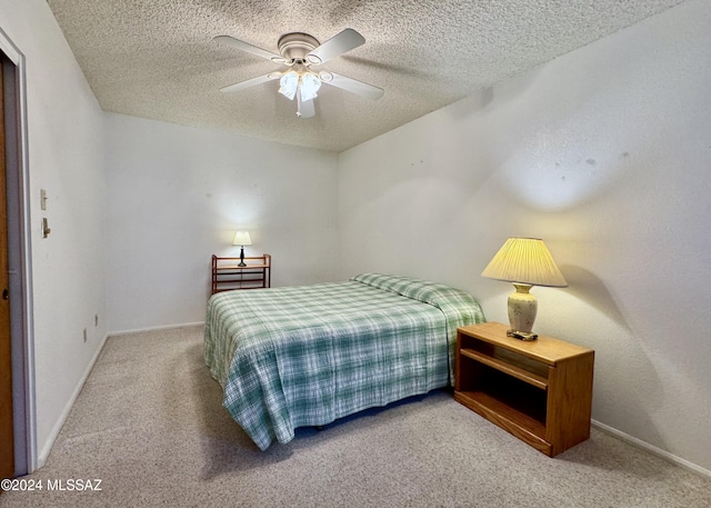 bedroom with ceiling fan, carpet floors, and a textured ceiling