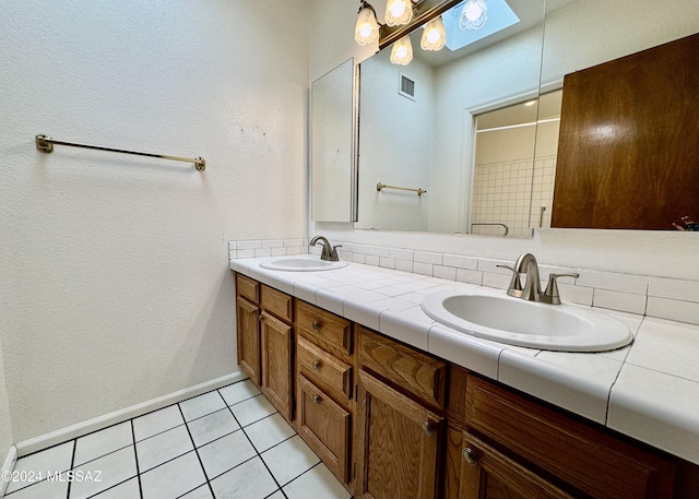 bathroom with tasteful backsplash, a skylight, tile patterned flooring, and vanity