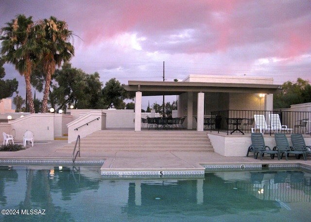 pool at dusk with a patio area