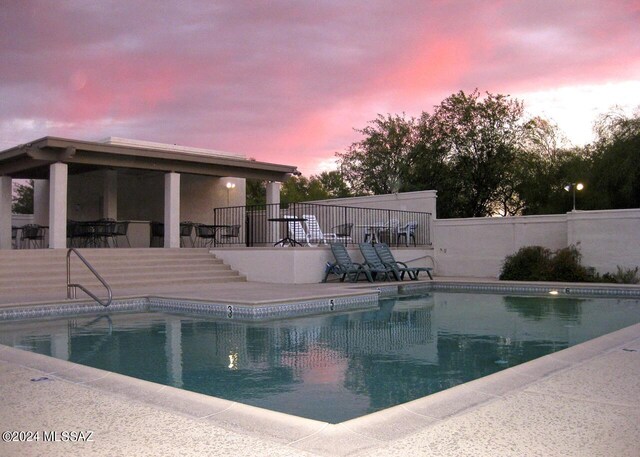 pool at dusk with a patio area