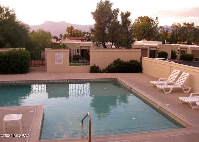 pool at dusk featuring a mountain view and a patio area