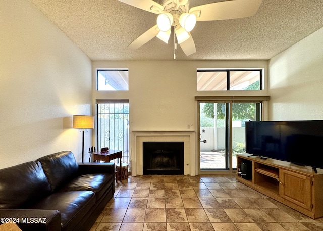 living room with a fireplace, a textured ceiling, plenty of natural light, and ceiling fan