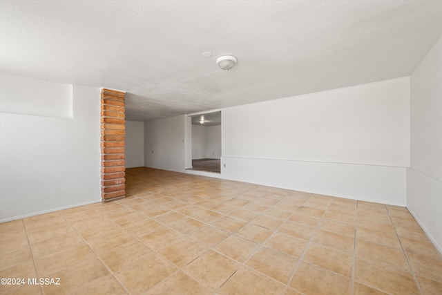 spare room with a textured ceiling and light tile patterned flooring