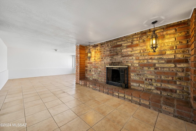 unfurnished living room featuring a textured ceiling, light tile patterned flooring, and a brick fireplace