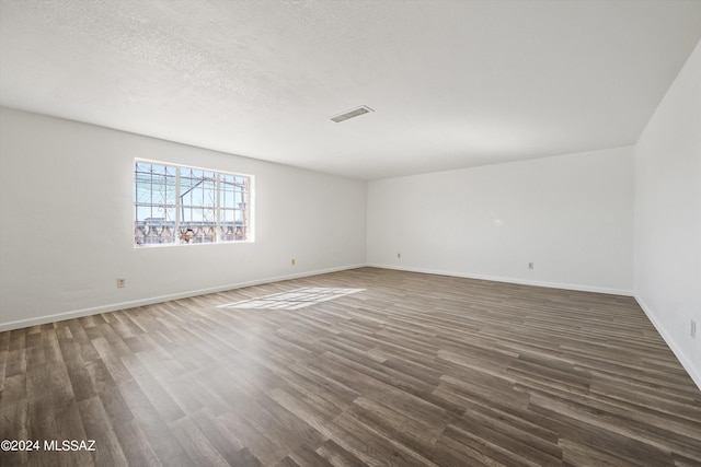 unfurnished room with a textured ceiling and dark hardwood / wood-style flooring