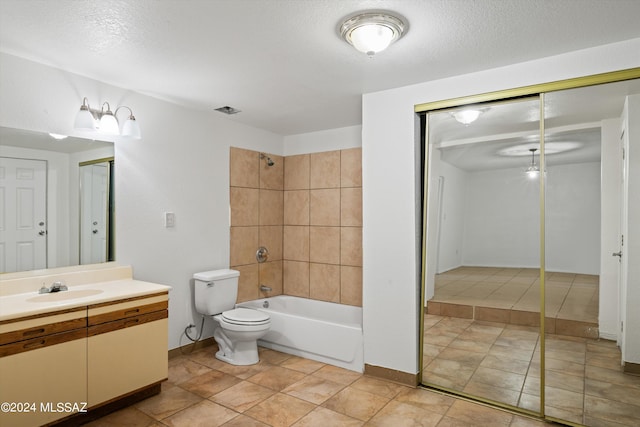 full bathroom featuring a textured ceiling, vanity, toilet, and tiled shower / bath