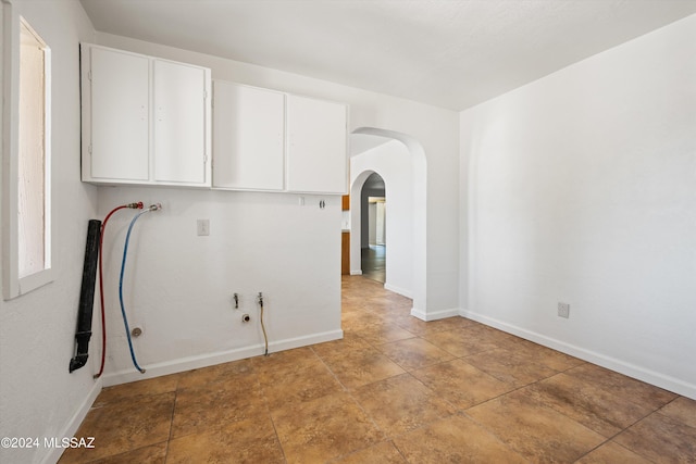 empty room featuring arched walkways and baseboards
