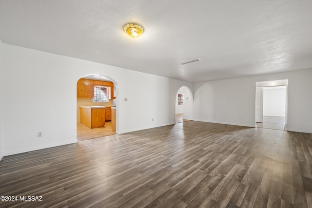 unfurnished living room featuring a textured ceiling and dark wood-type flooring