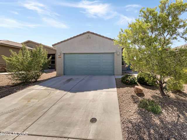 view of front of property featuring a garage, driveway, a tiled roof, and stucco siding