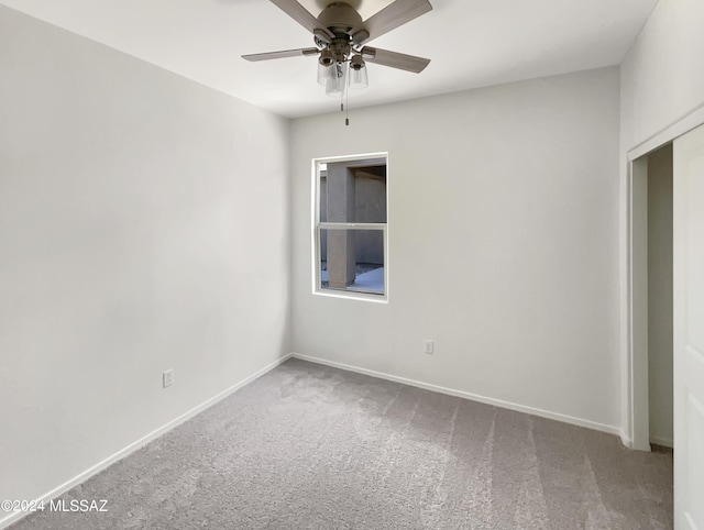 carpeted spare room with baseboards and a ceiling fan