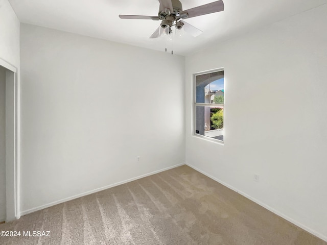 empty room with a ceiling fan, light carpet, and baseboards