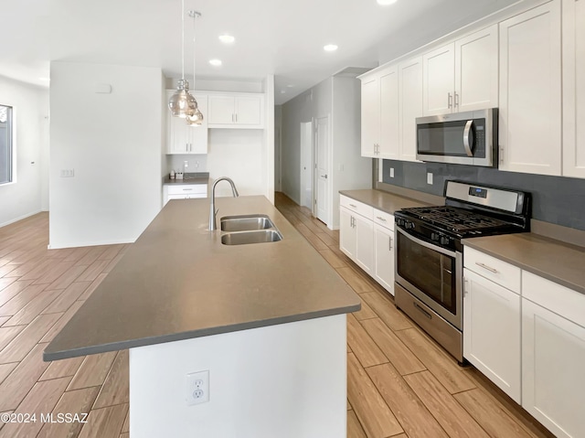 kitchen with an island with sink, wood tiled floor, stainless steel appliances, and a sink