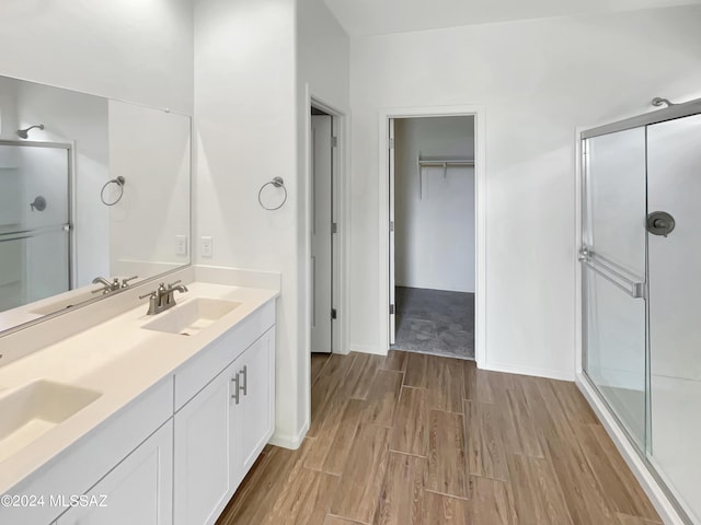 full bathroom featuring a sink, a shower stall, and wood finished floors