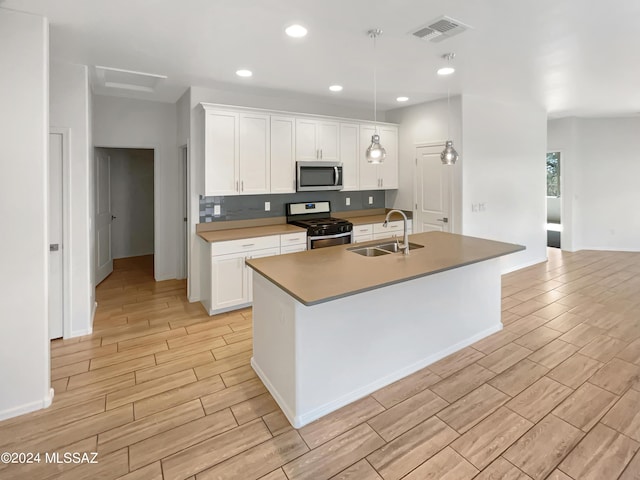 kitchen featuring visible vents, appliances with stainless steel finishes, wood finish floors, white cabinetry, and a sink